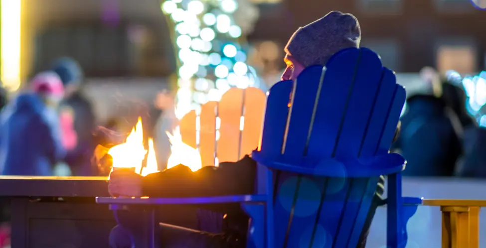 Personne assise autour d'un feu de camps avec un chocolat chaud